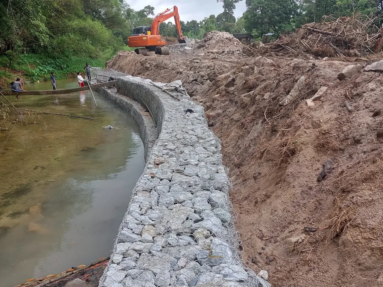 Struktur gabion mengikut lengkung tebing sungai, dipasang di kaki tebing dengan jengkaut bekerja di belakang.
